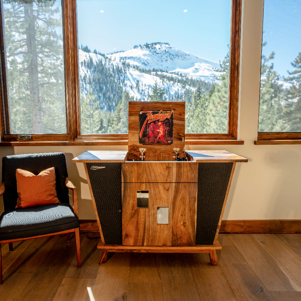 Streamline HiFi Rambler model stereo console in a beautiful mountain home. A view of snow capped mountains is seen through the large windows behind the console.